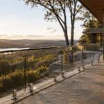 Modern glass railing on a balcony overlooking a scenic sunset landscape.