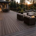 Spacious backyard deck with outdoor furniture and scenic forest view at sunset.